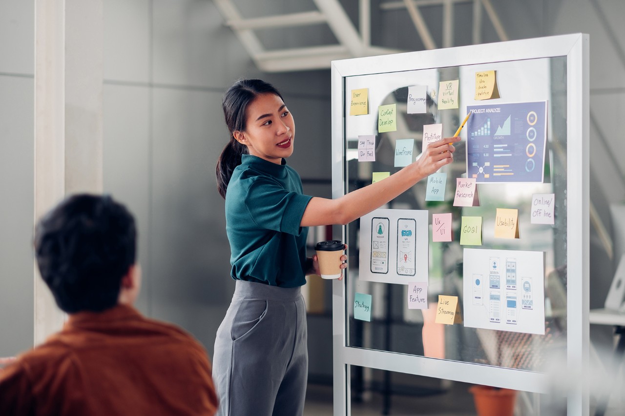woman-presentation asian ux developer and ui designer presenting mobile app interface design on whiteboard in meeting at modern office.Creative digital development mobile app agency.digital transformation