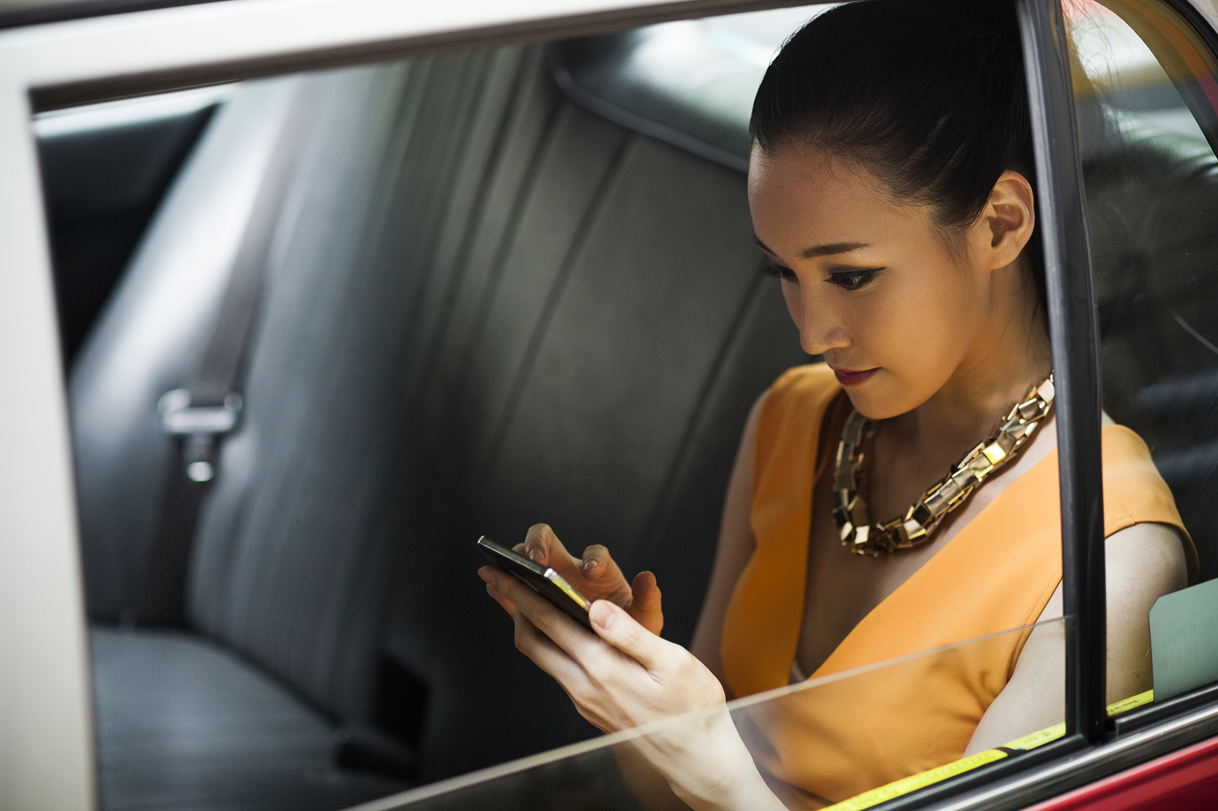 A woman watching her phone in a cab