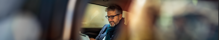 Man in a car looking at his tablet and smiling